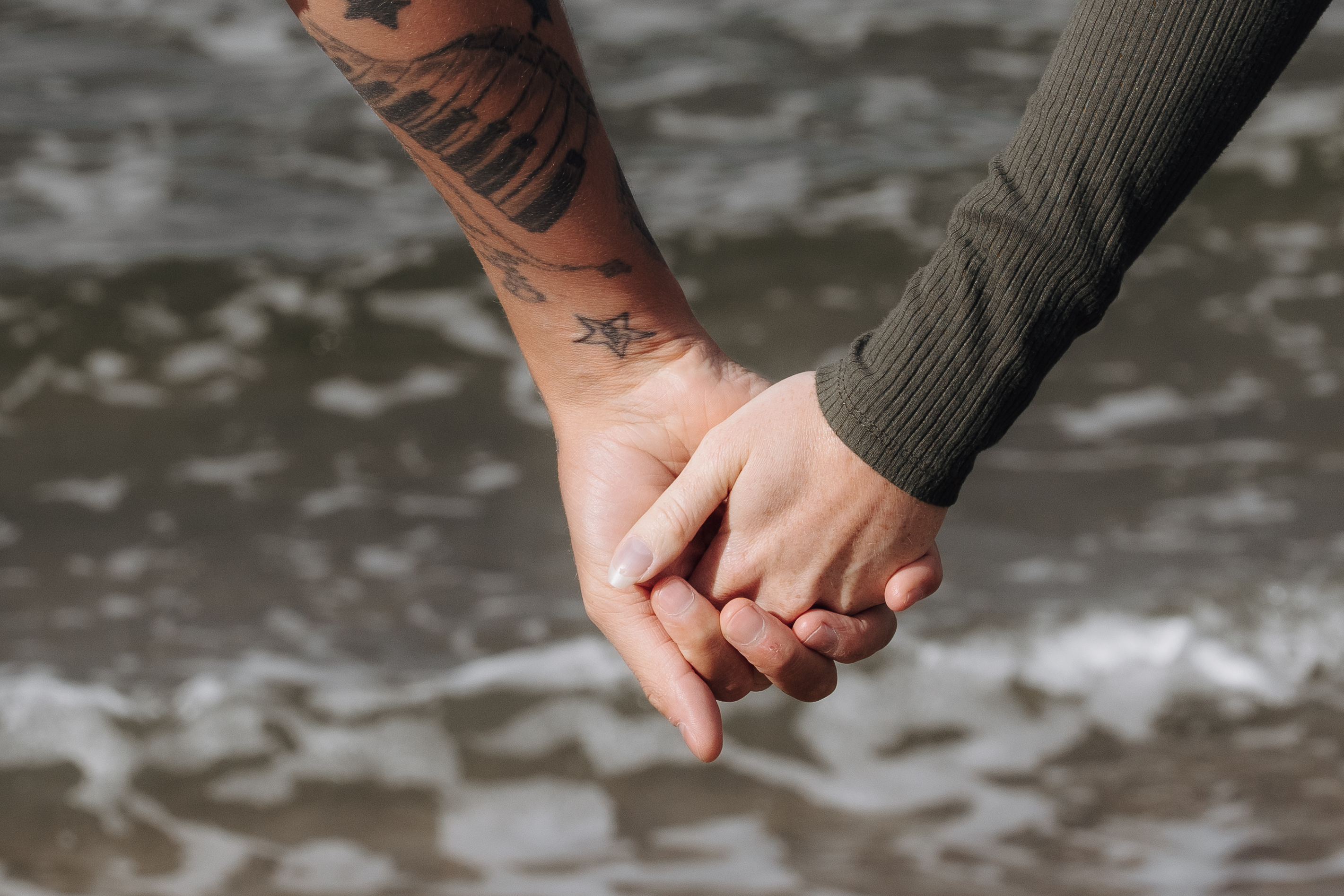 Hand in Hand – Hochzeitsfotografie von Pure Weddings Die Hochzeitsfotografen Stephie und Robert halten sich am Strand die Hände