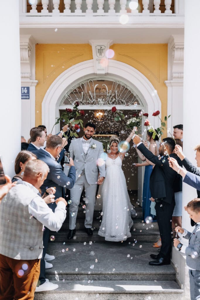 Auszug des Brautpaares aus dem Standesamt Mandlstraße München unter Seifenblasen – Hochzeitsfotograf Freising
