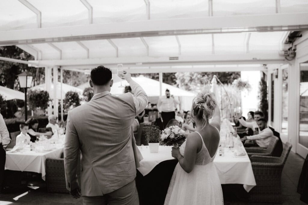 Brautpaar beim Anstoßen während der Hochzeitsfeier im Aumeister München (Schwarz-Weiß) – Hochzeitsfotograf Freising