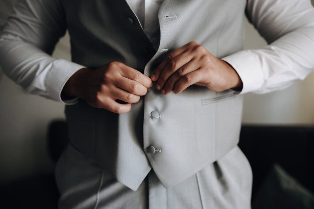 Bräutigam zieht seine Weste an vor der Hochzeit in München – Hochzeitsfotograf Freising