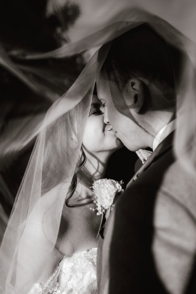 Brautpaar küsst sich unter dem Schleier, intimer Moment, Hochzeitsfotograf Freising