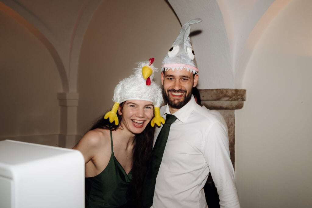Gute Laune an der Fotobox: Gäste posieren lachend mit lustigen Hai- und Hühner-Hüten